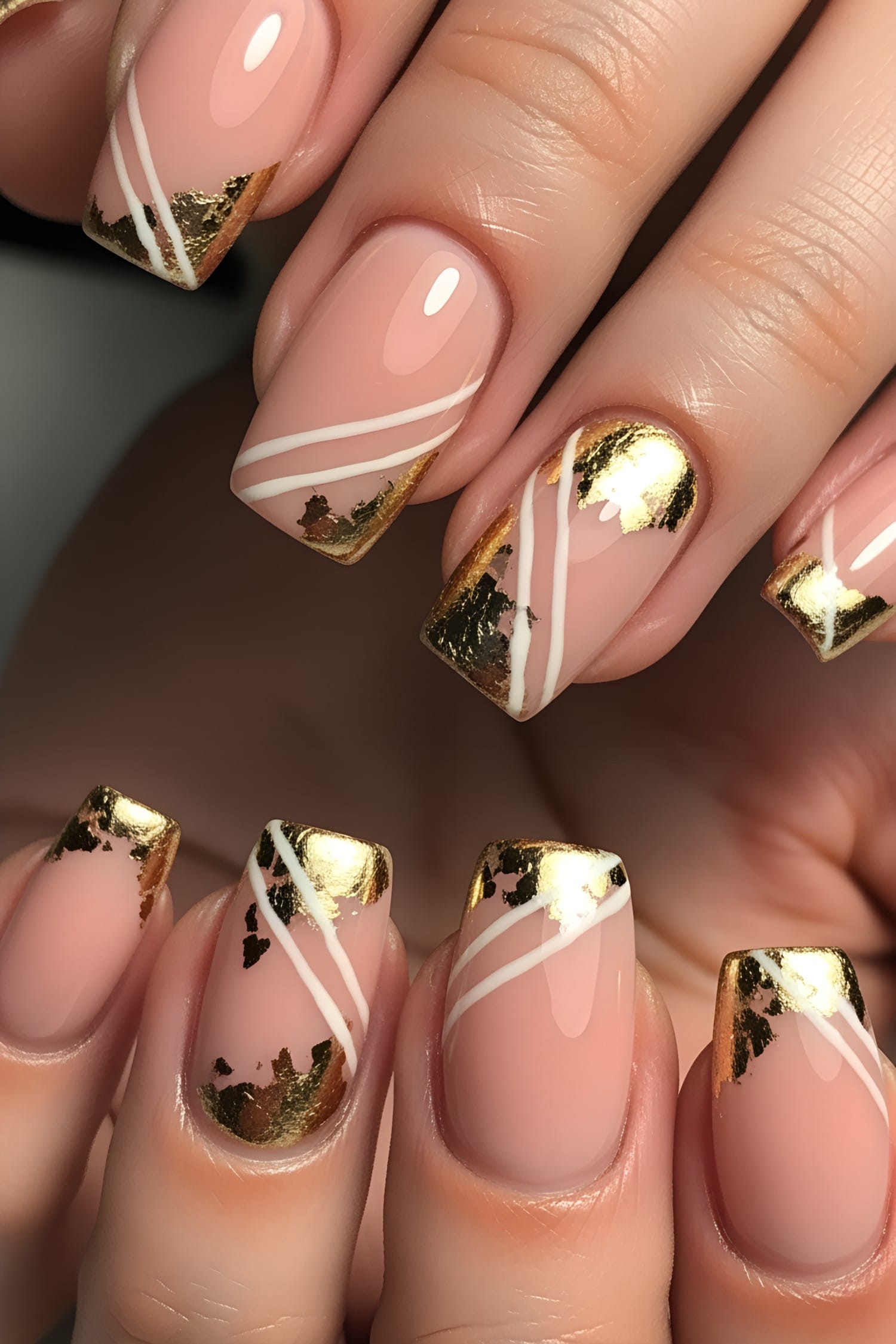 Gold foil french tips and white diagonal stripes on nude pink nails