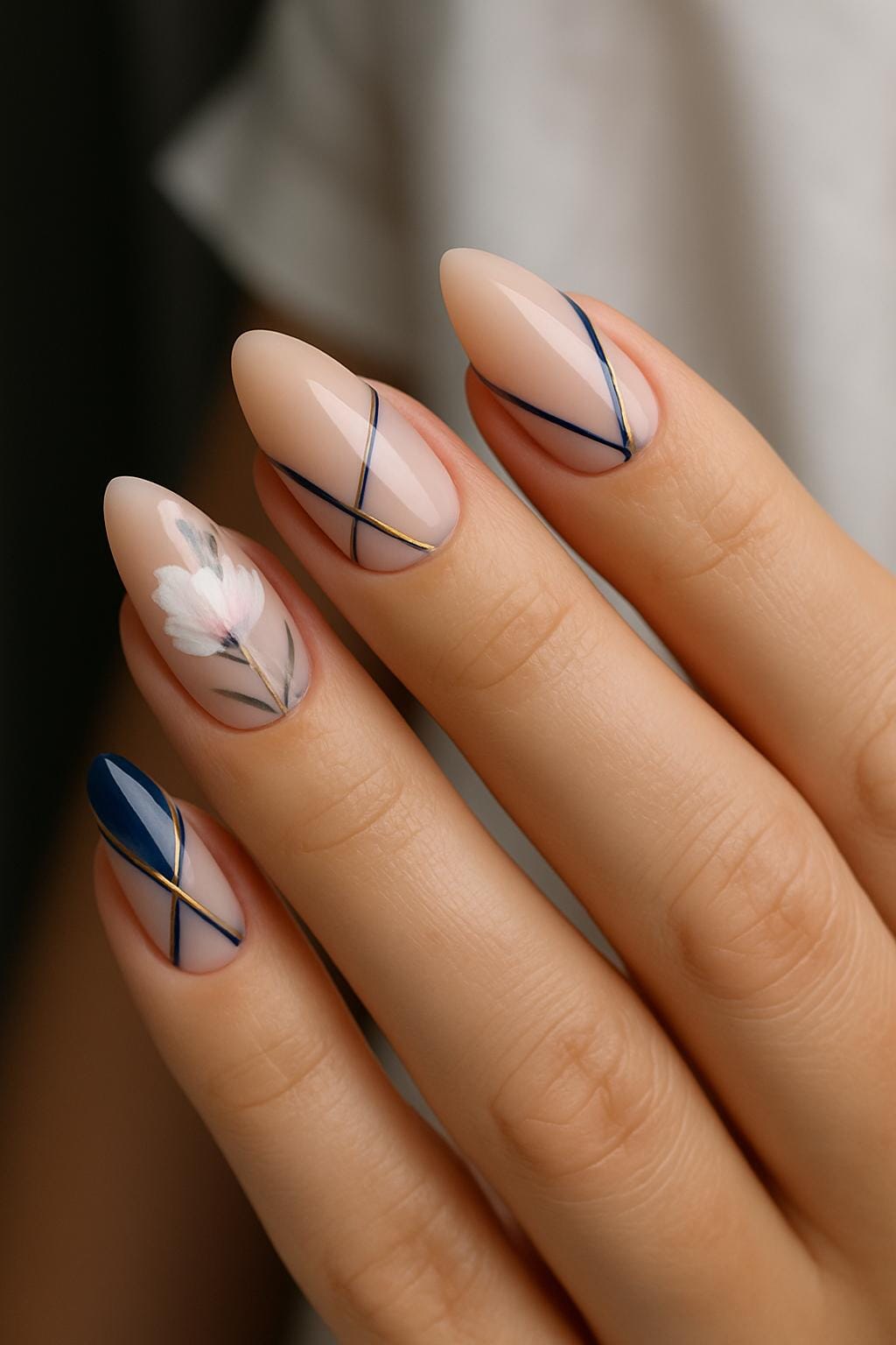 Almond nails with navy and gold stripes, plus one white floral accent