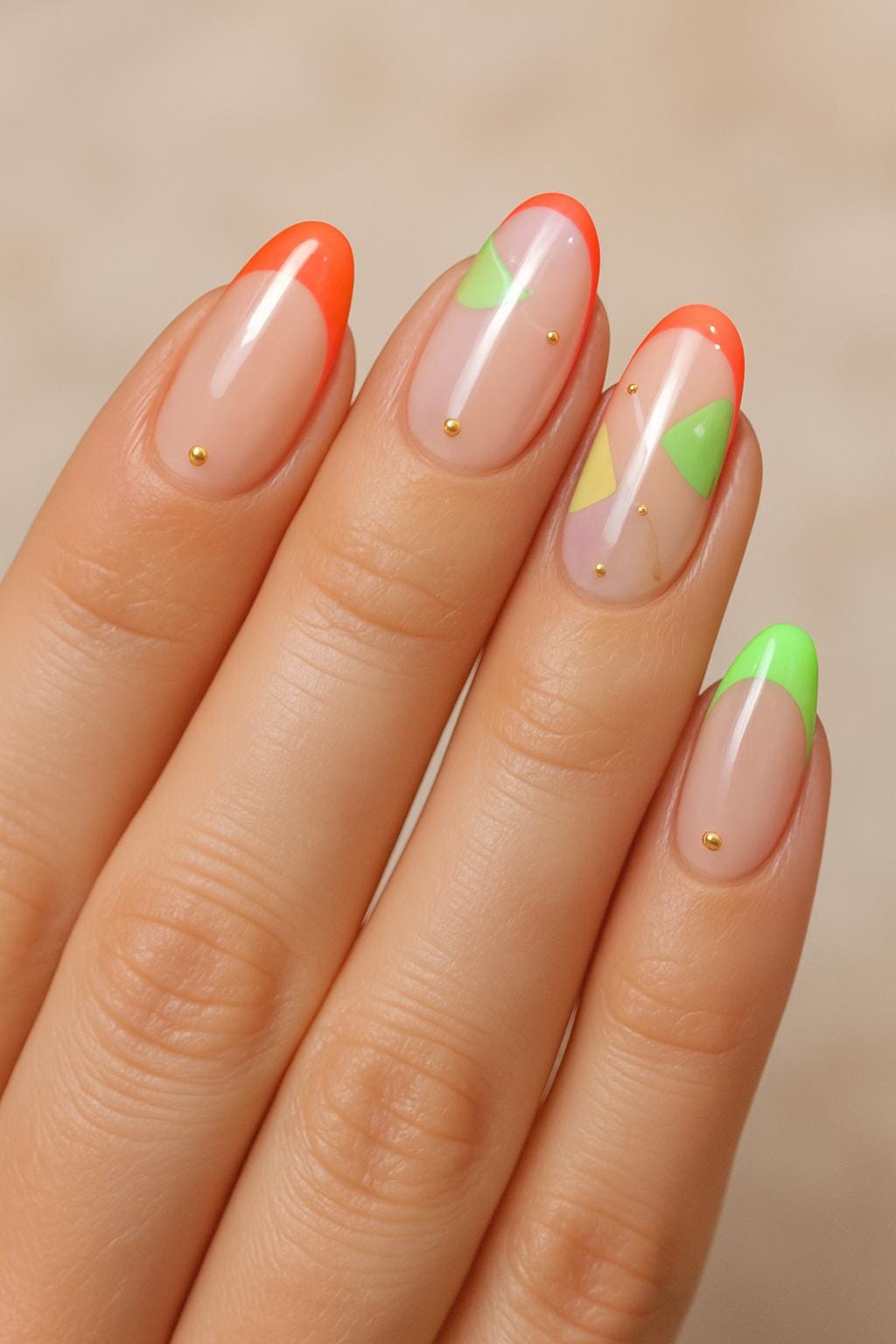 Neon French tips with abstract green and yellow shapes and tiny gold studs