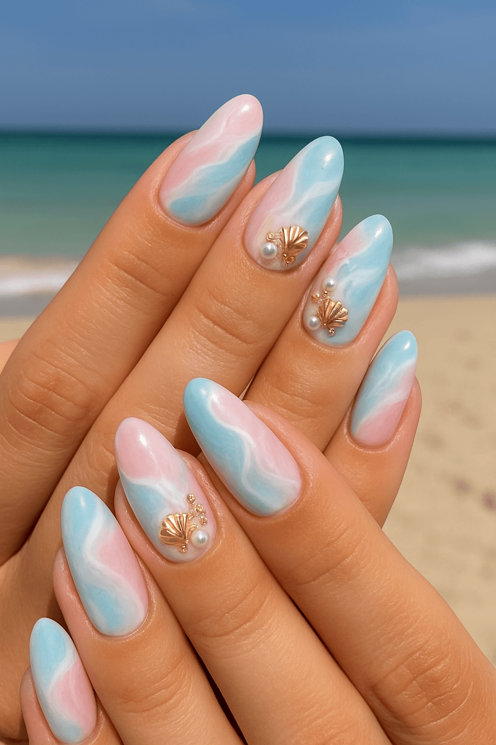 Pastel blue and pink beach-themed nails with gold seashell and pearl accents