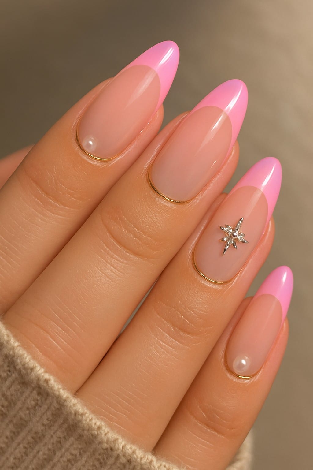 Pink french tip nails with gold accents, pearl beads, and a star-shaped charm