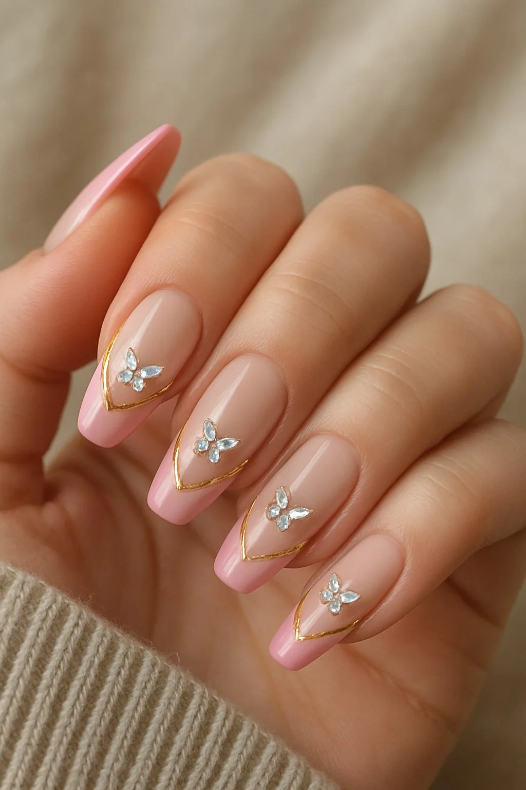 Pink French tips with gold lines and butterfly-shaped crystal charms